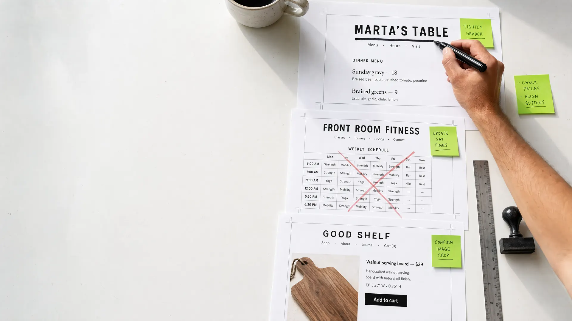 Overhead view of the Corner Office proof table: printed website pages for Marta's Table, Front Room Fitness, and Good Shelf being marked up by hand with a black marker, green sticky notes, and a red correction X.